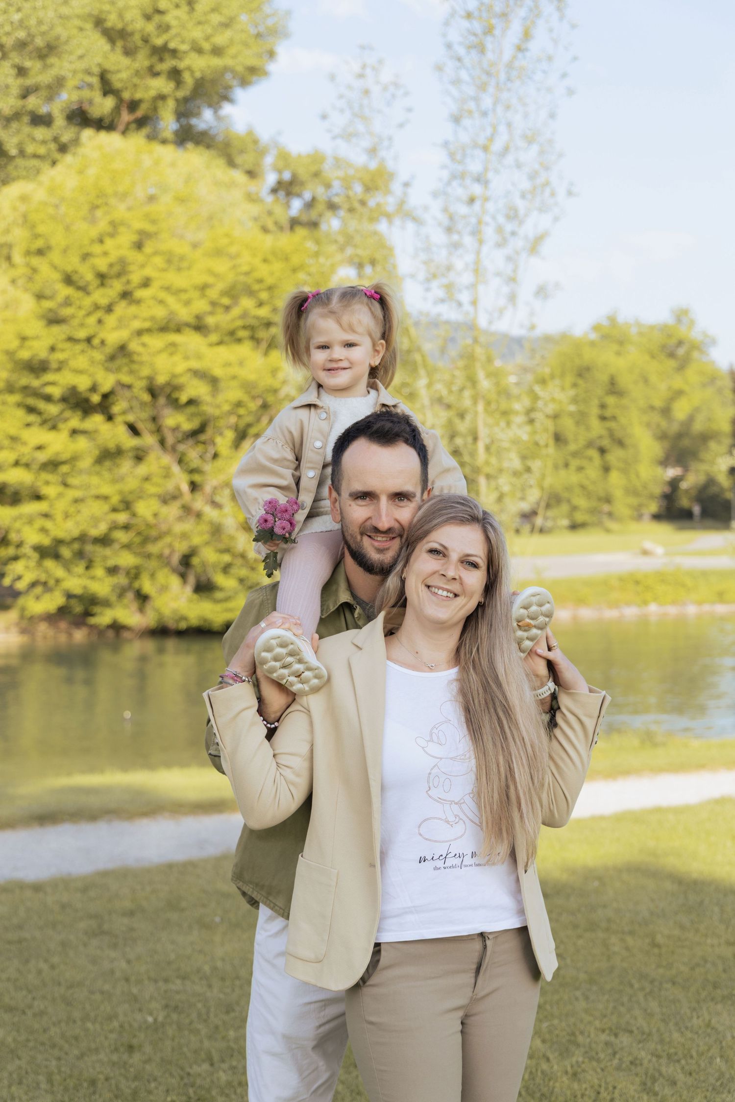 Parents with their daughter sitting on their shoulders during a family photoshoot in a Swiss park.