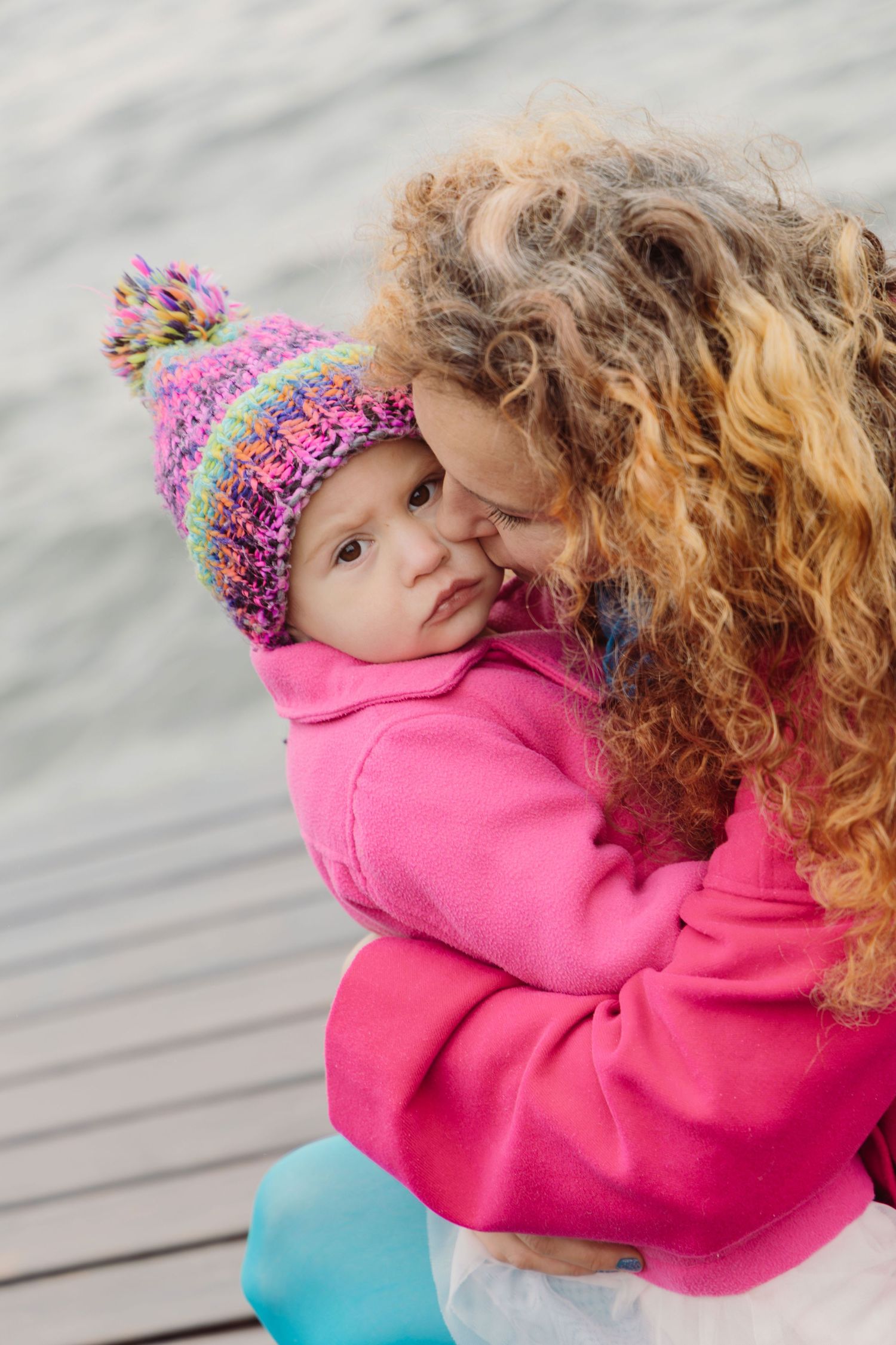 Mother kissing her daughter during a tender family photoshoot in winter.
