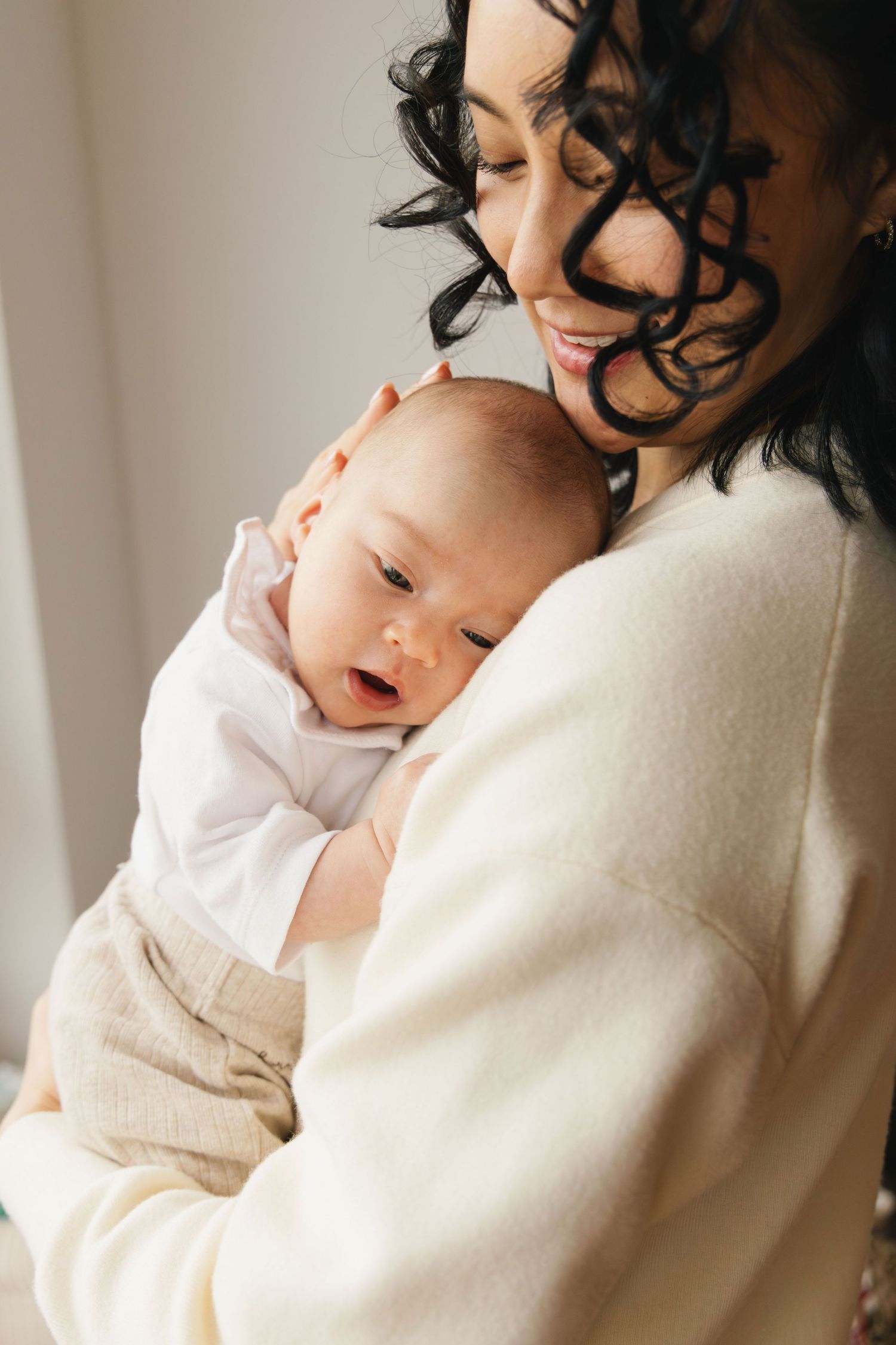 Mother holding her newborn with the baby resting on her chest during a newborn photoshoot.