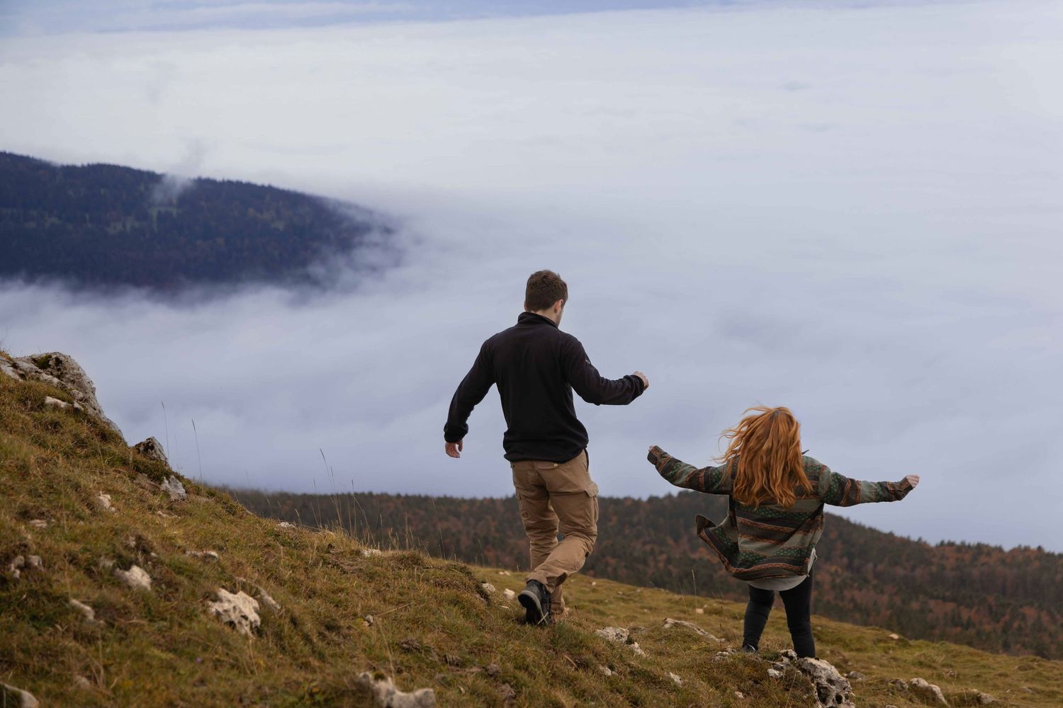Couple playfully running during a hiking photoshoot in the Swiss mountains.
