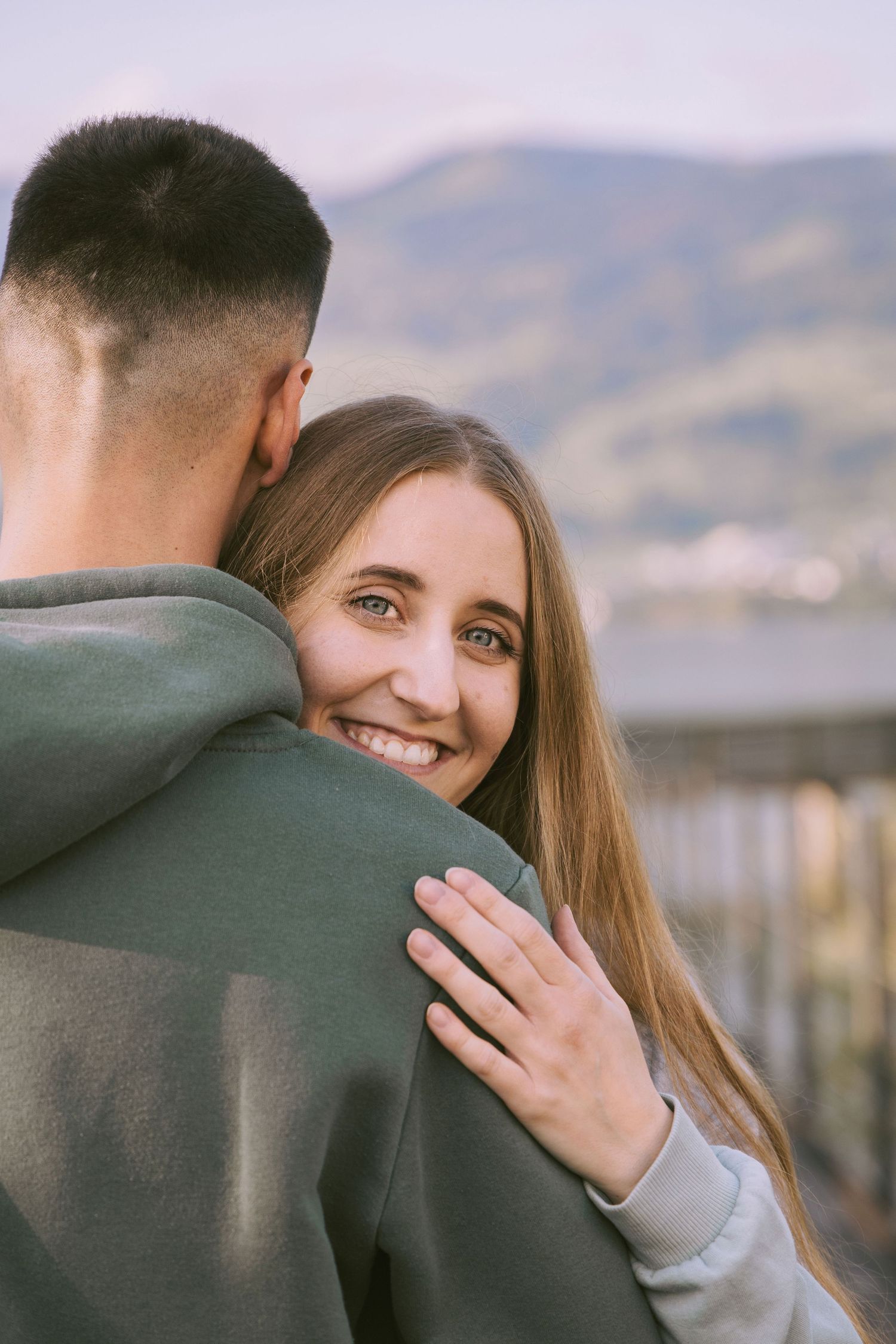 Woman hugging her partner on a wooden bridge during a romantic couples photoshoot.