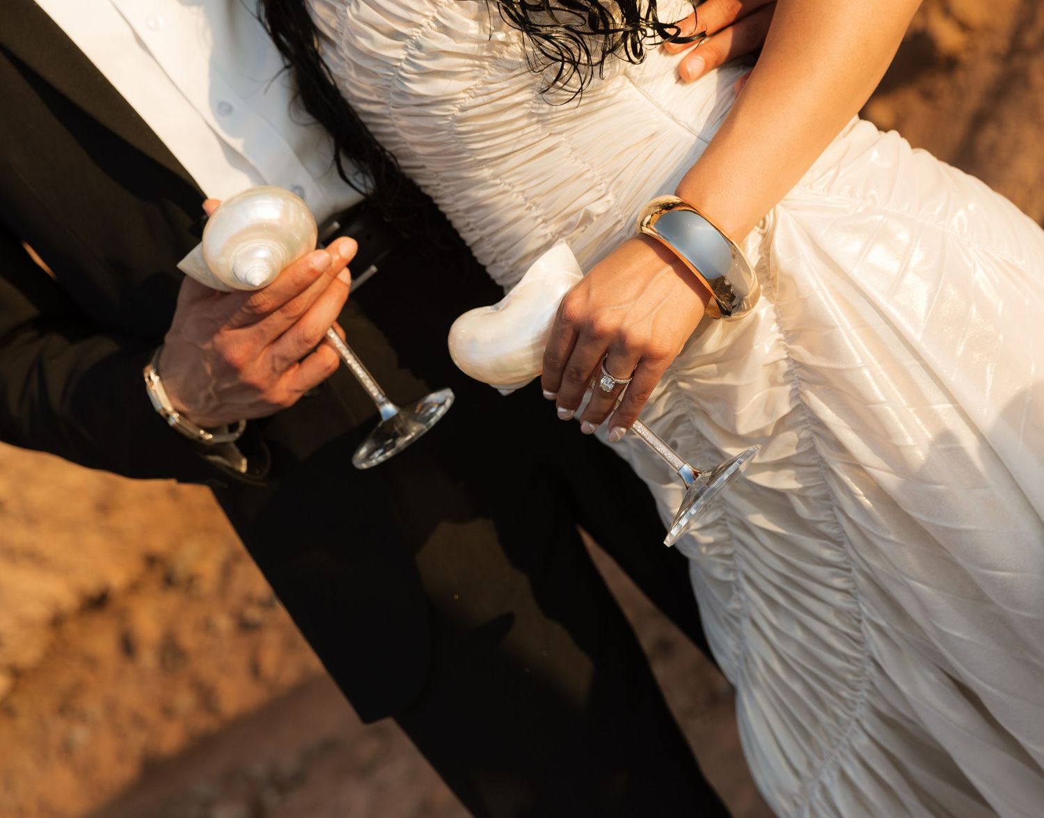 A bride and groom hold hands during their wedding ceremony in warm ambient lighting.