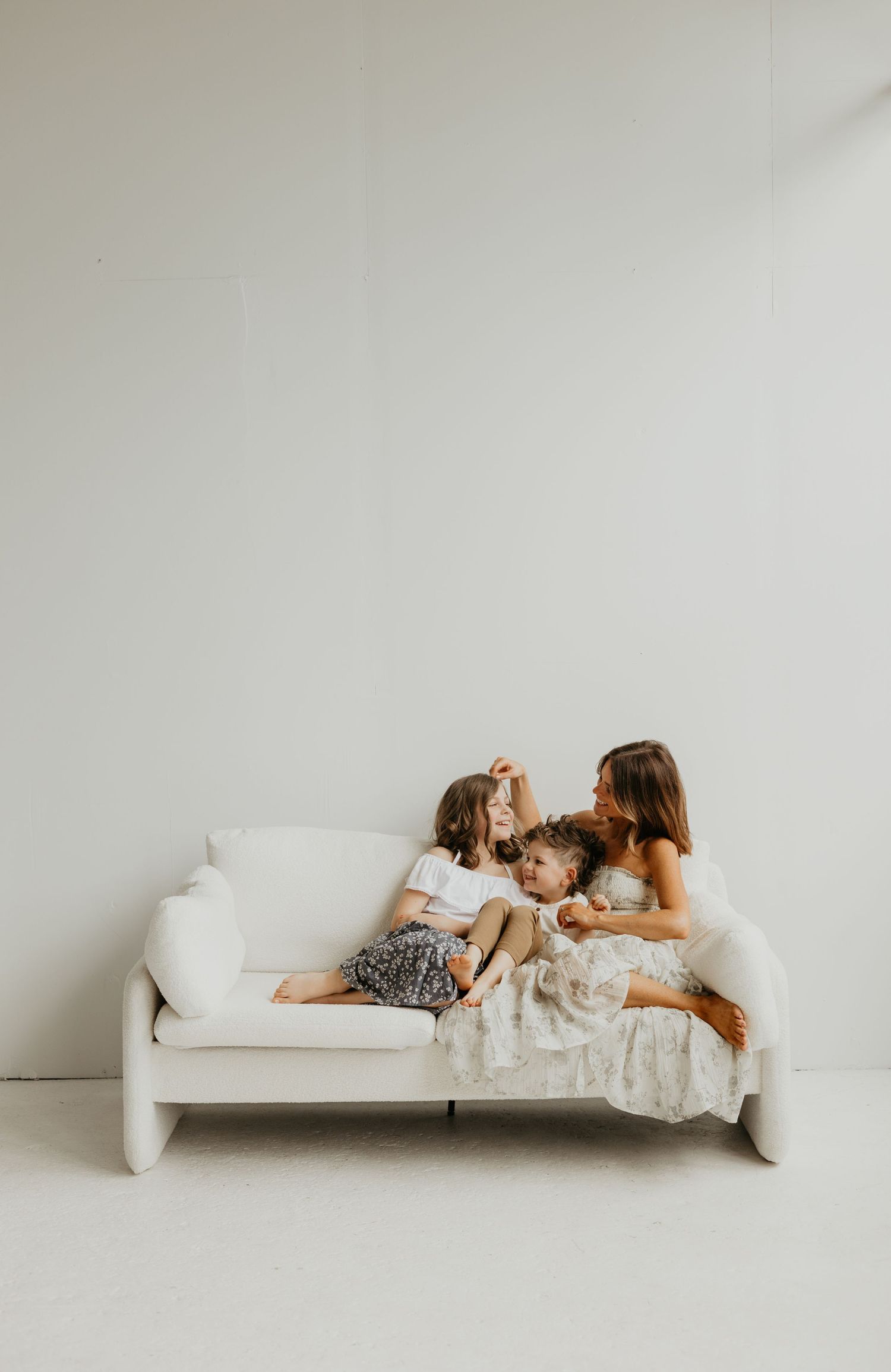 A series of minimalist photos showing a tender moment between parent and child on a white couch against a light backdrop.