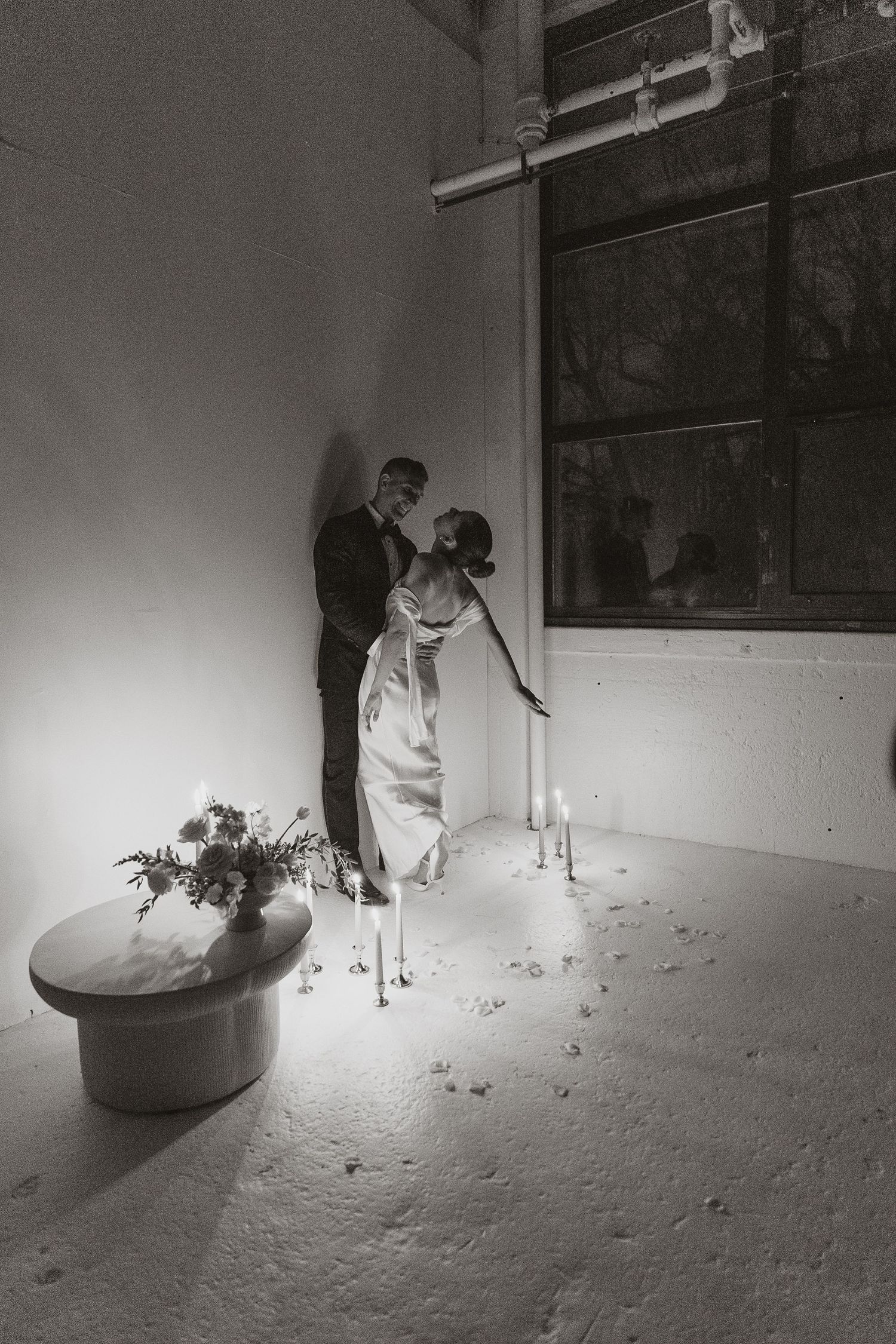 Black and white photo of couple in formal wear with candlelit setting.