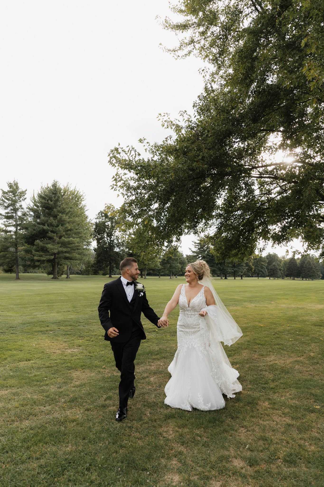 Playful wedding sequence on grassy lawn with flowing white dress and veil.