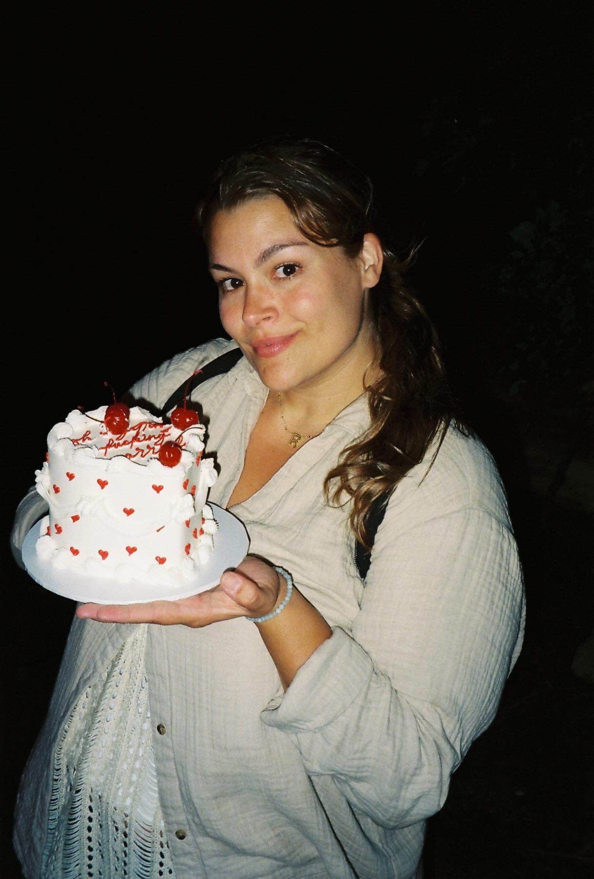 A sequence of photos showing someone in a white shirt holding and eating a white cake decorated with red strawberries.