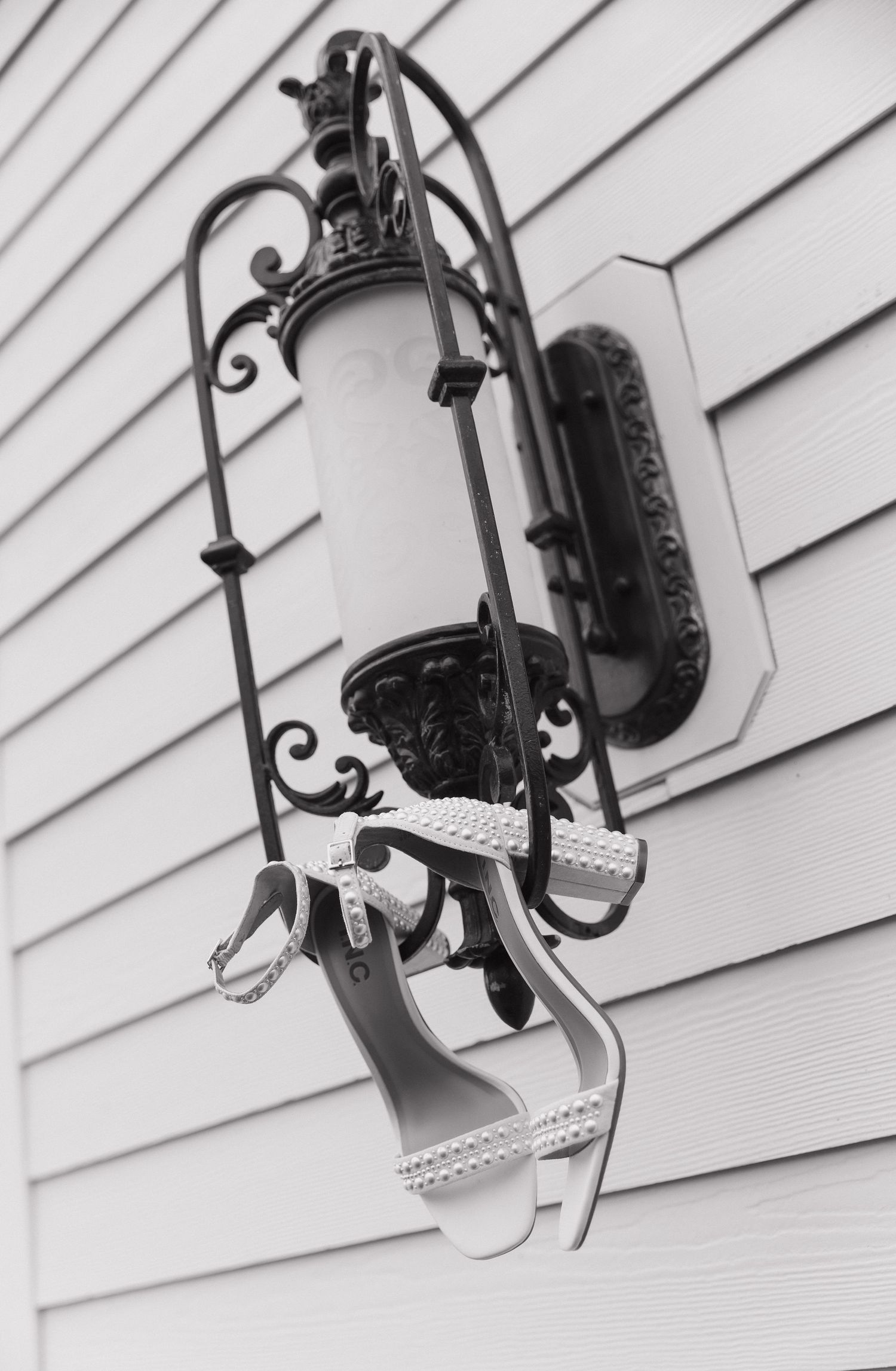 Black wrought iron outdoor wall sconces mounted on white siding in a row.