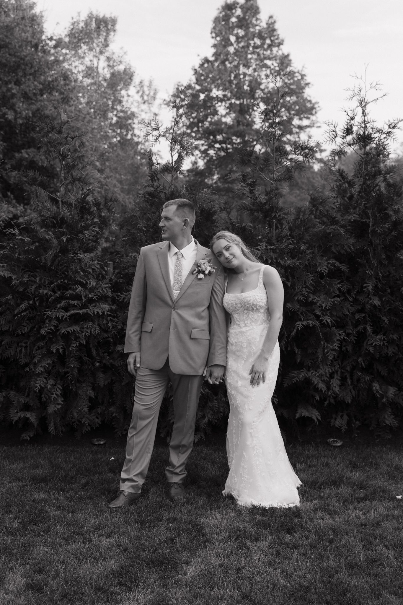 Black and white photo of newlyweds posing together in garden setting.