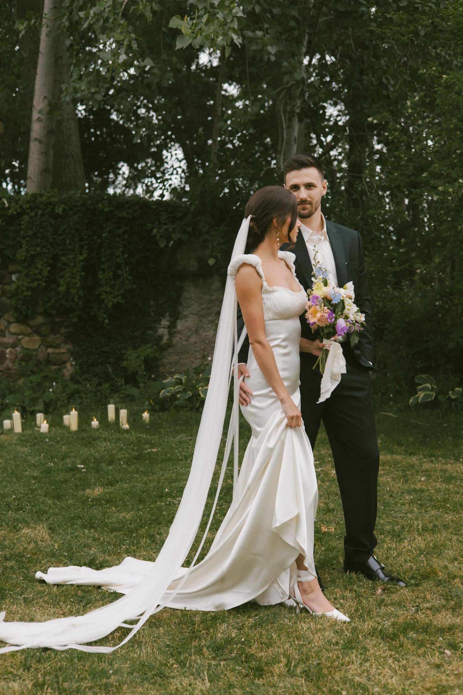 Candid wedding moments captured in a green garden setting with flowing veil.