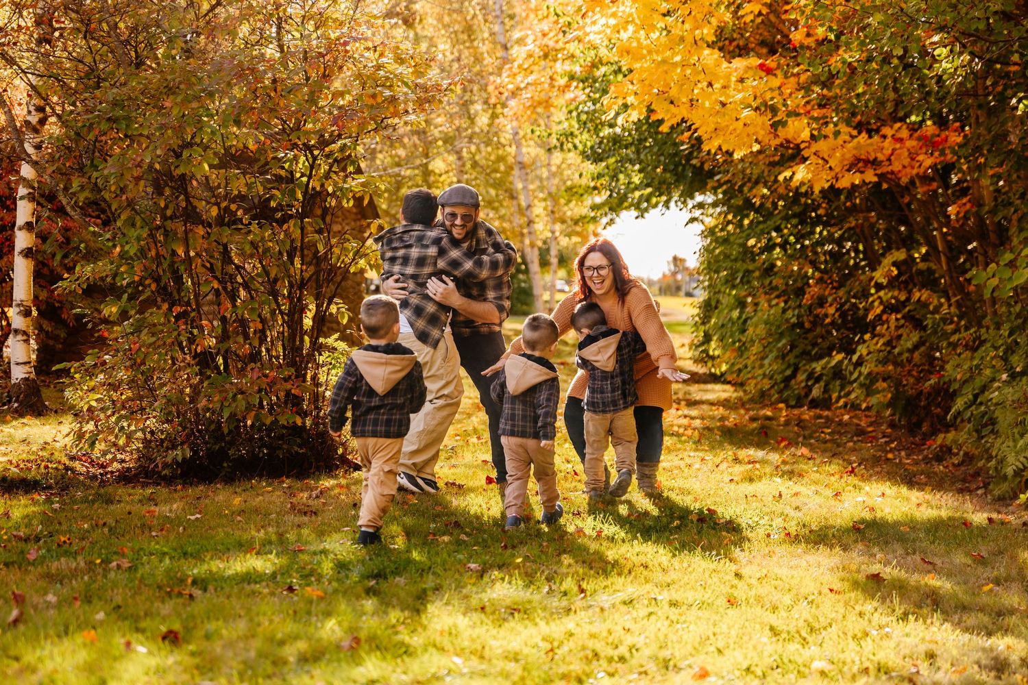 Family playing outdoors in autumn forest with colorful fall foliage on a sunny day.