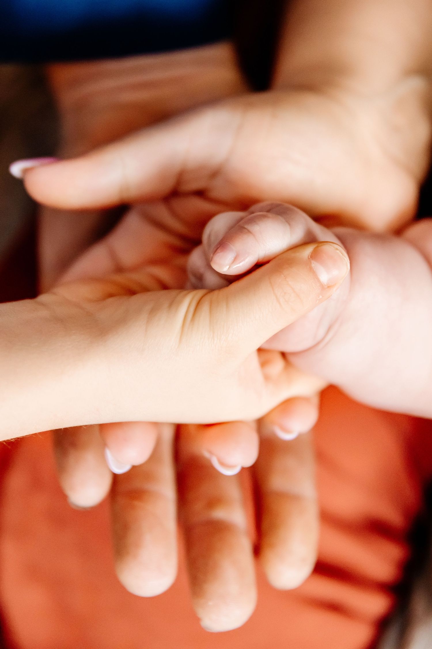 Close-up of newborn baby hand gently held by parents hands, symbolizing new family bond and love.