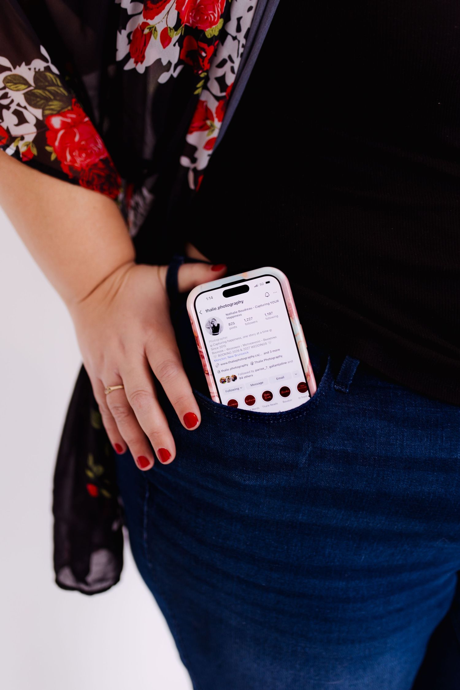 Thalie photography Woman in floral kimono with red nails holding smartphone in jeans pocket.