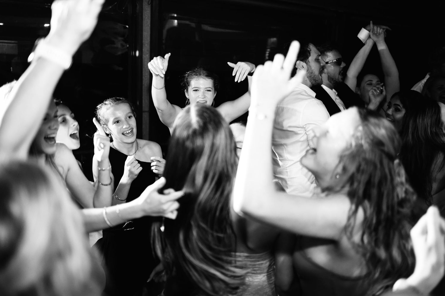 Wedding guests dancing and celebrating joyfully on the dance floor during a lively wedding reception.