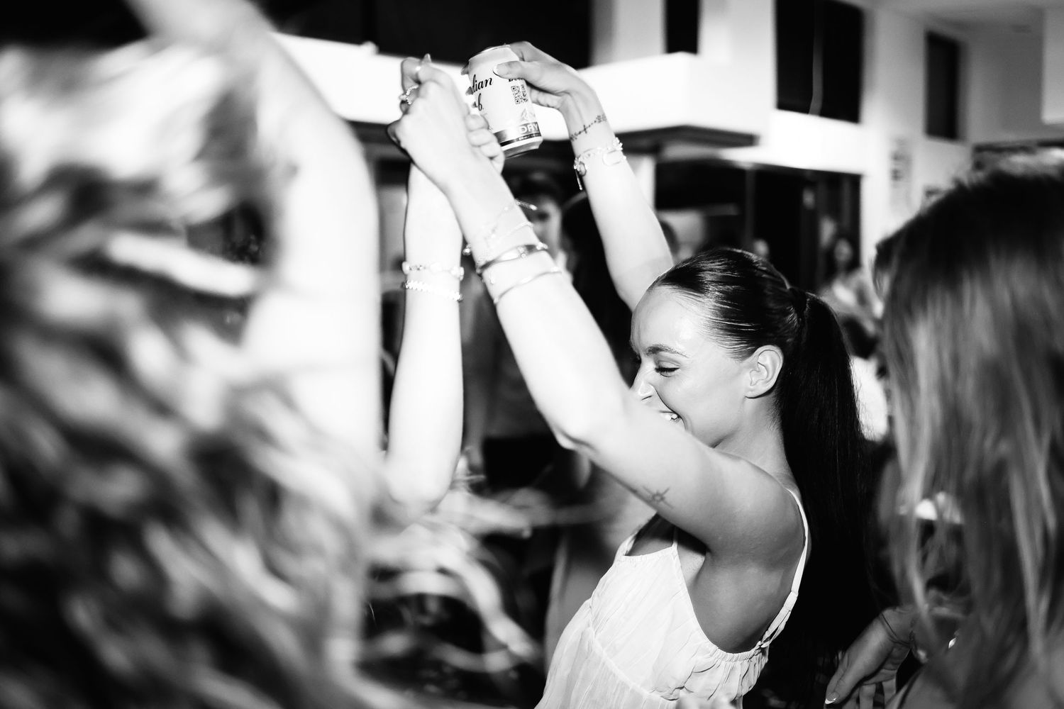 Woman smiling and raising a glass at a celebration in a black and white photo.