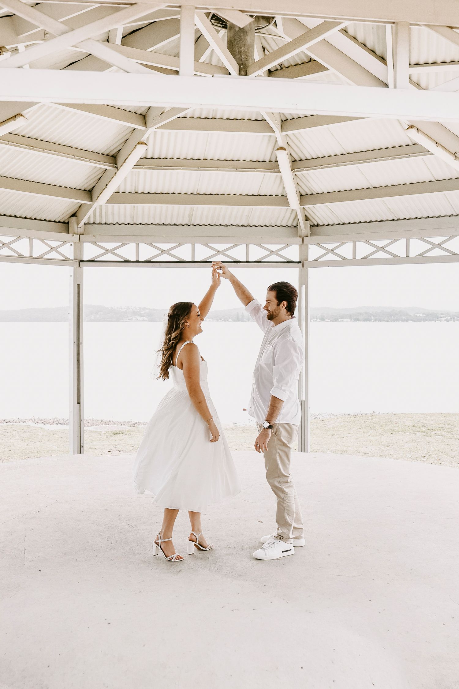 Bride and groom dancing under a waterfront pavilion on their wedding day.