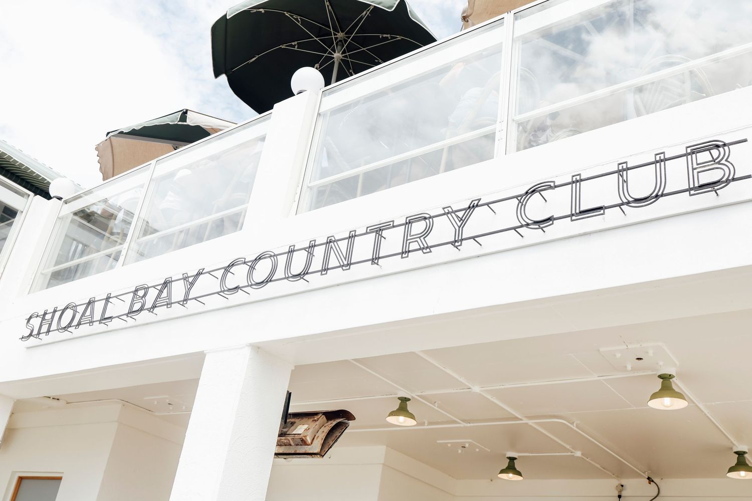Shoal Bay Country Club exterior sign on a white building with balcony.