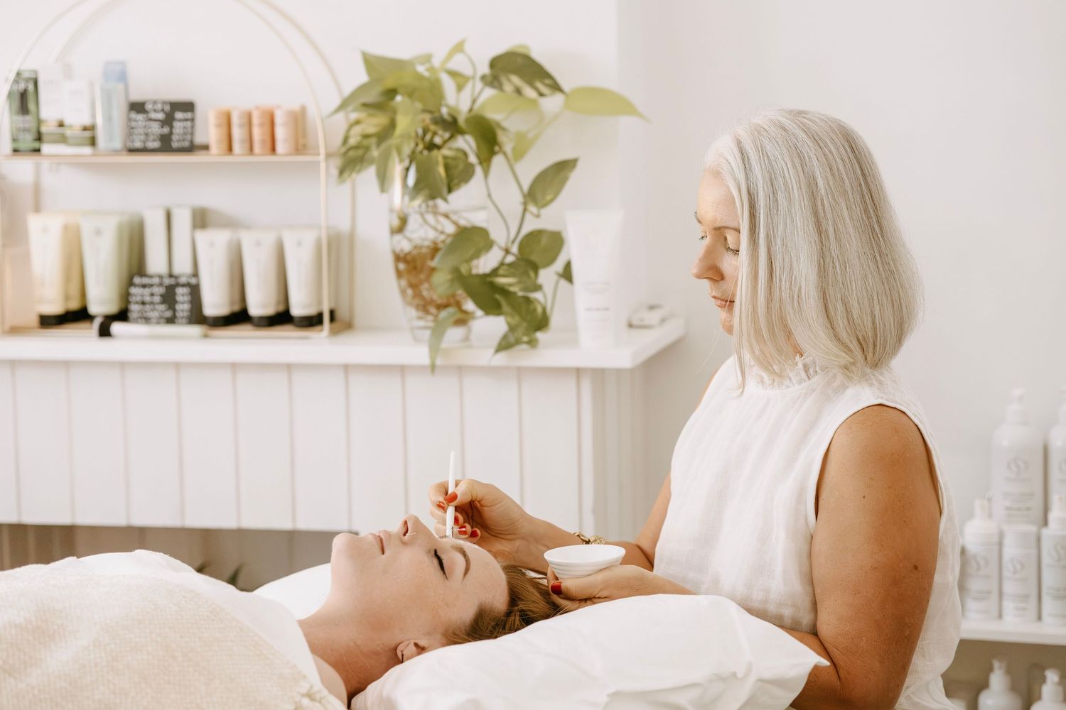 Female esthetician applying facial treatment to a client in a bright, modern spa.