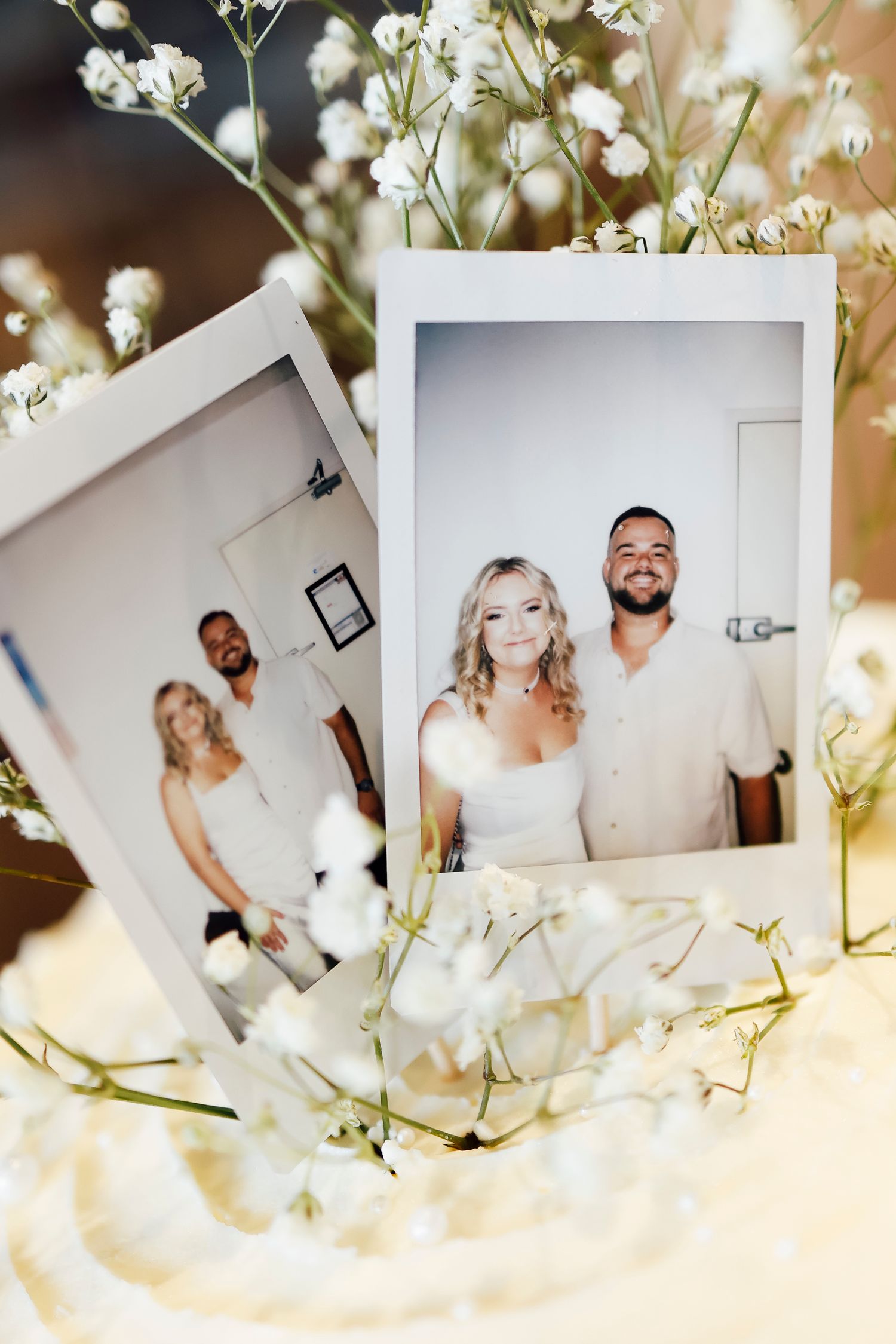 Polaroid wedding photos of bride and groom surrounded by white baby's breath flowers.