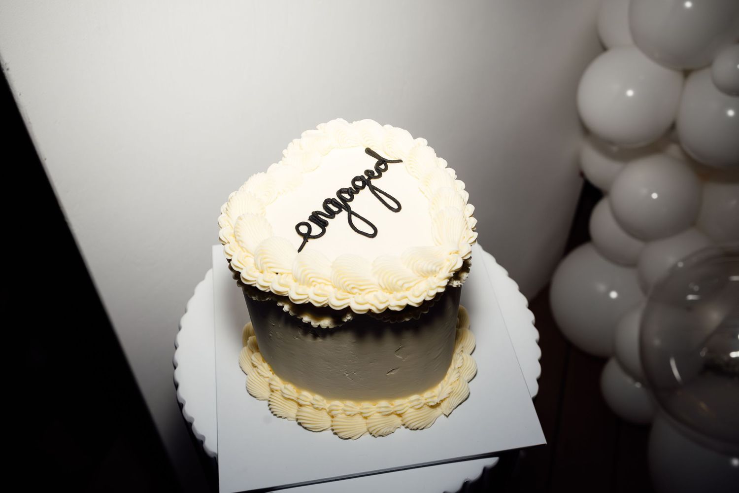 Heart-shaped engagement cake with 'engaged' written in chocolate on white frosting.