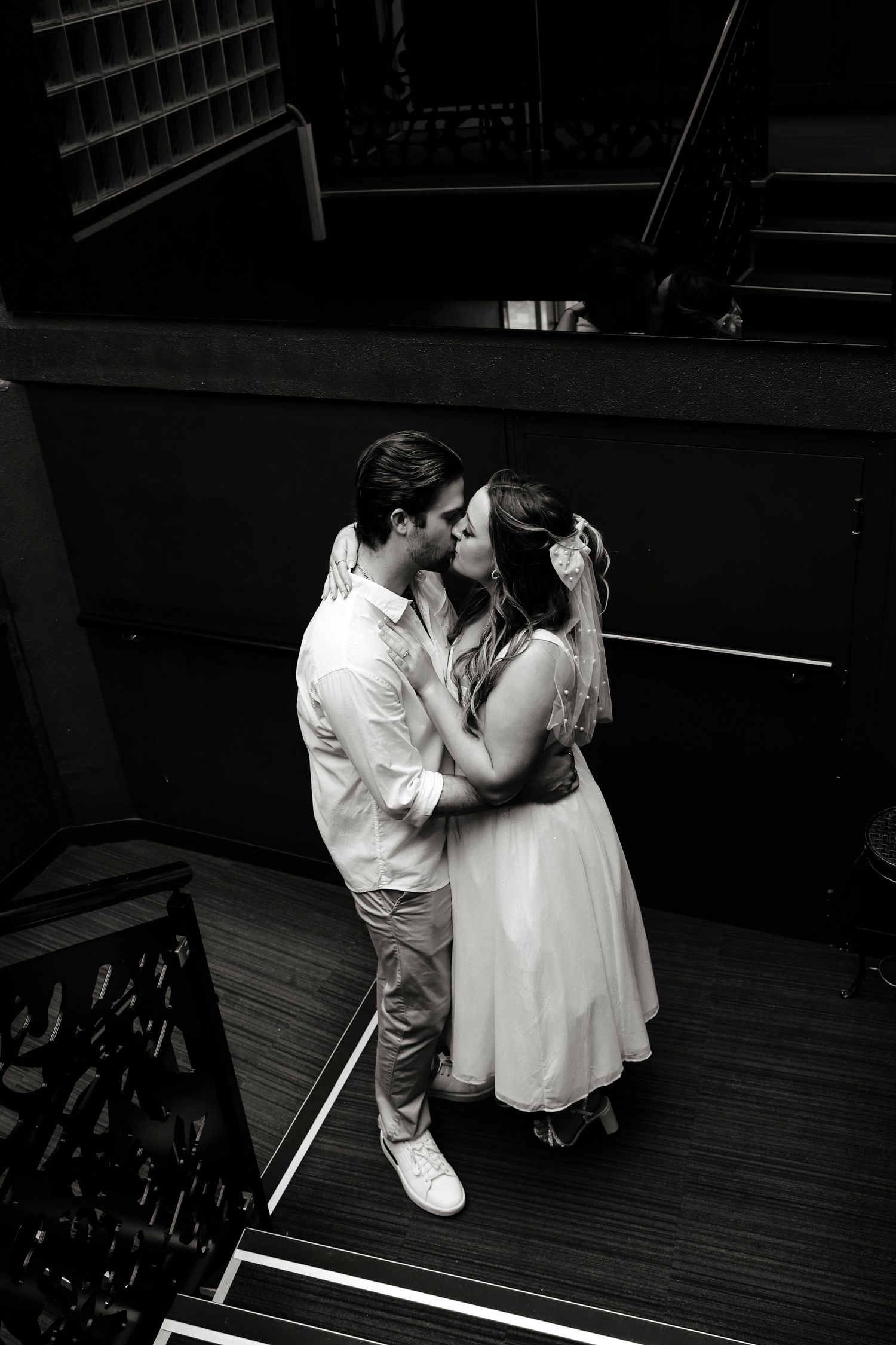 Black and white photo of bride and groom sharing a kiss on a staircase.