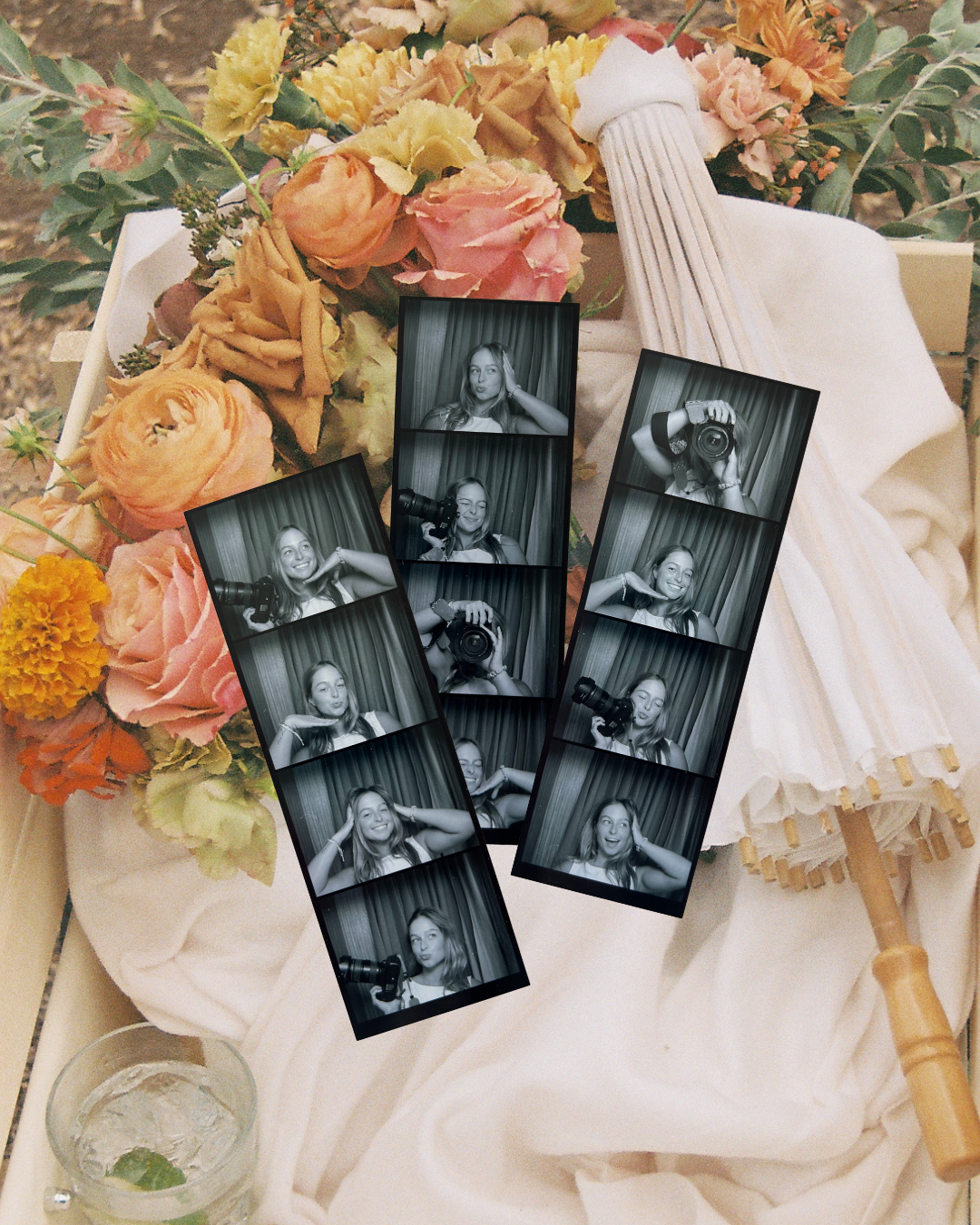 Black and white photo booth strips displayed on white fabric with colorful floral arrangement.