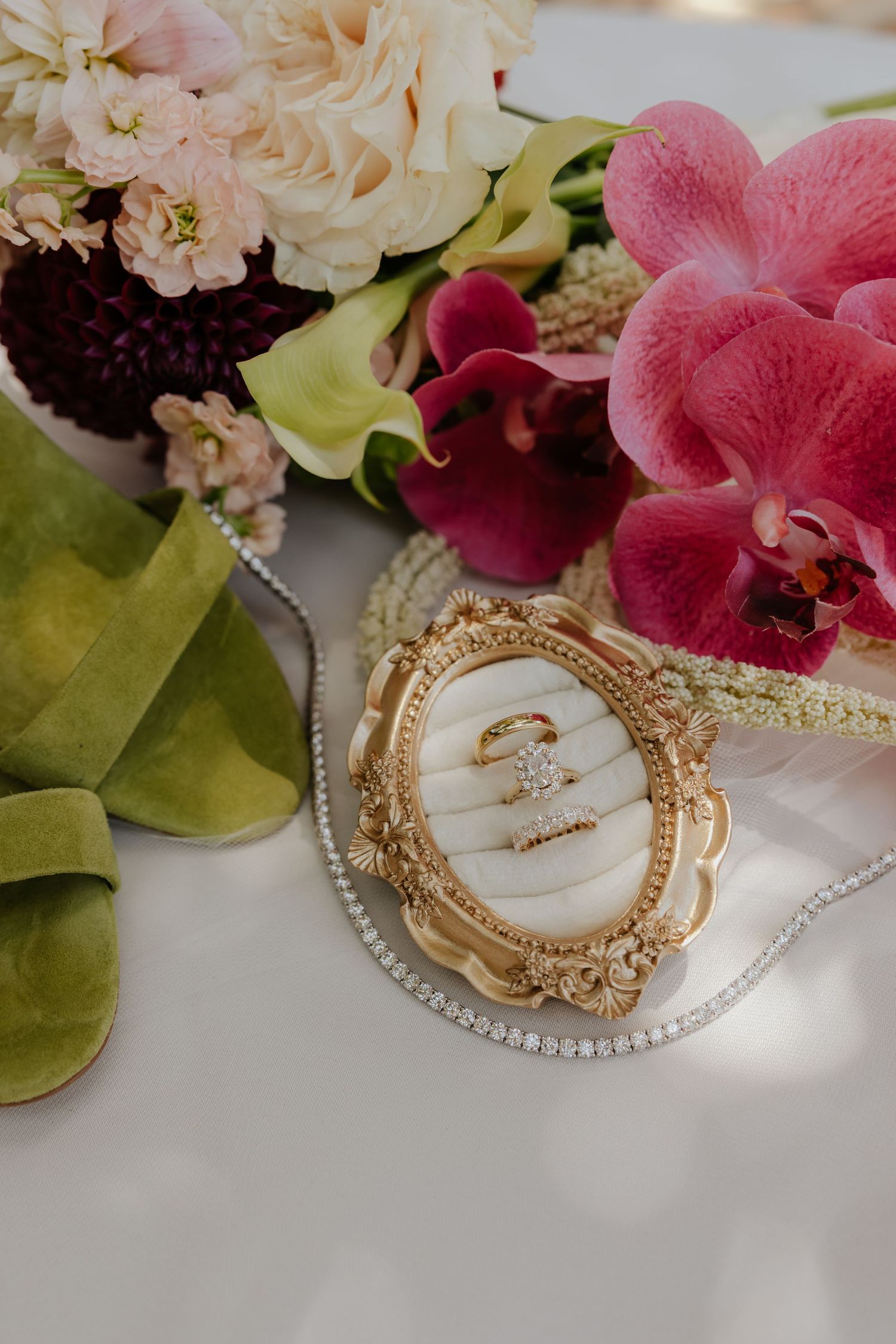 Gold ornate ring dish with diamond engagement ring surrounded by pink orchids and roses.