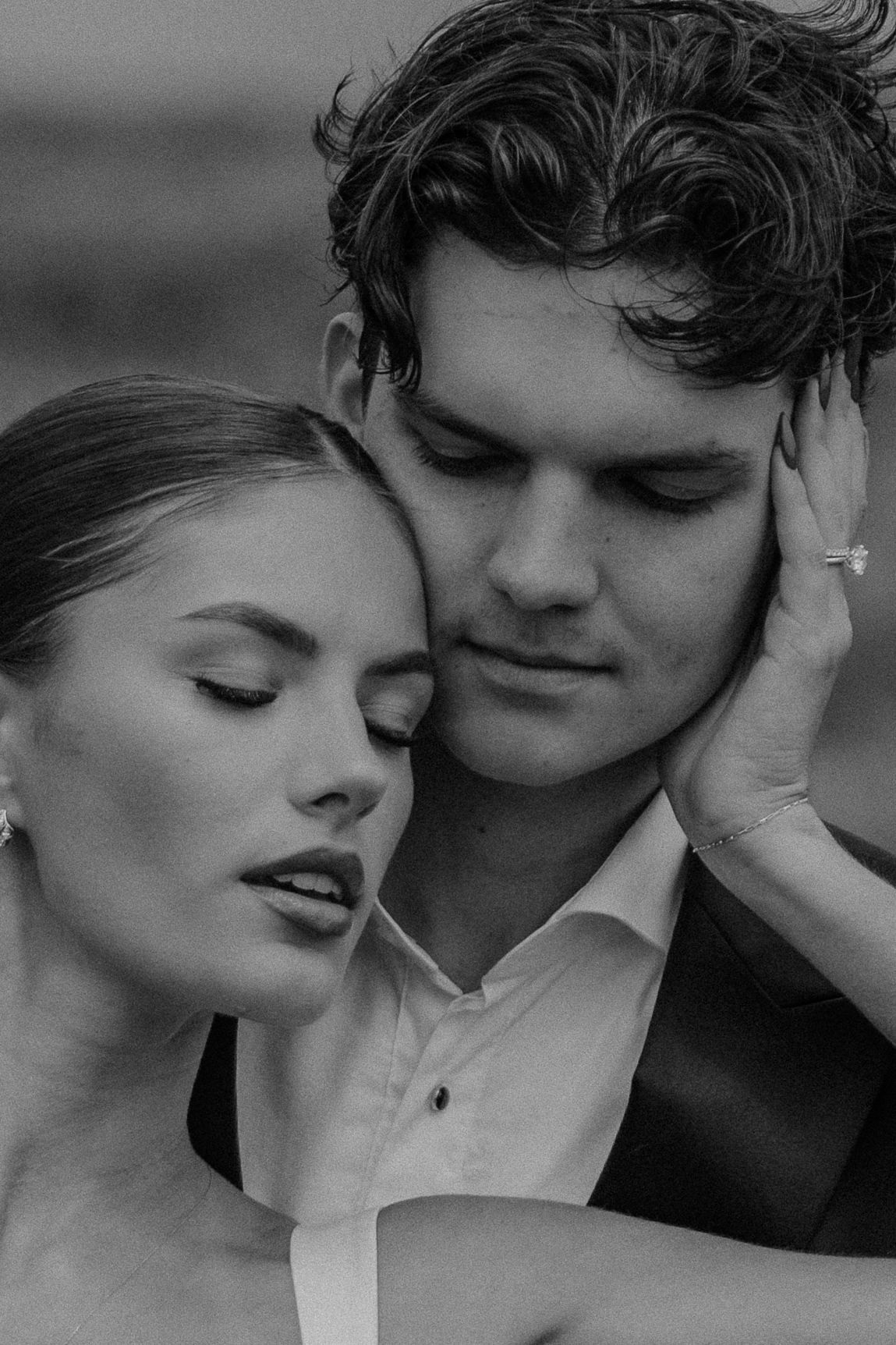 Black and white close-up of elegant couple with eyes closed in tender intimate moment.