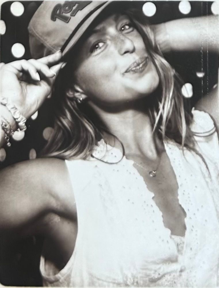 Black and white photo of woman in cap and white top posing at party.