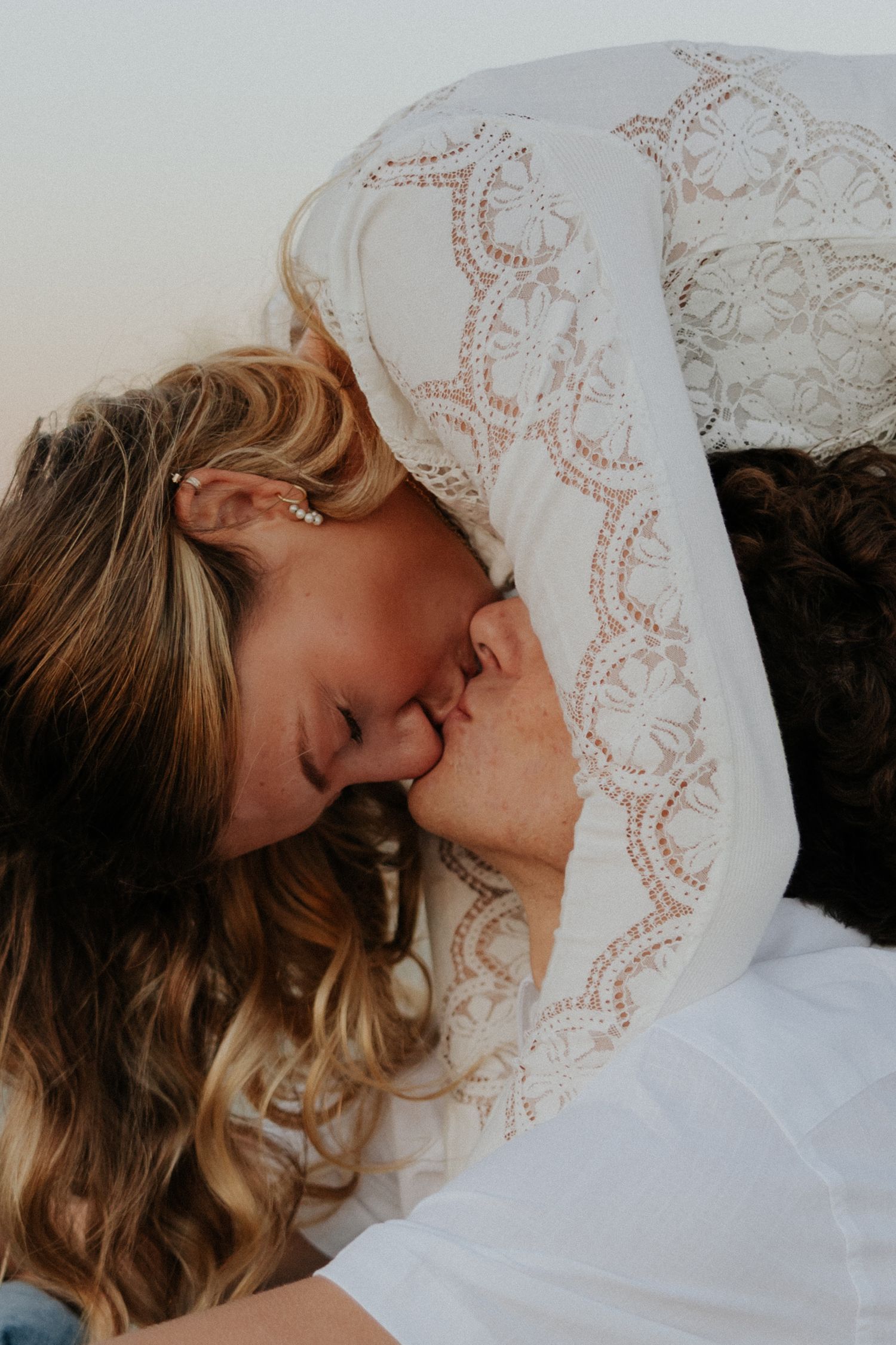 Close-up of romantic couple sharing tender kiss outdoors in soft natural light.