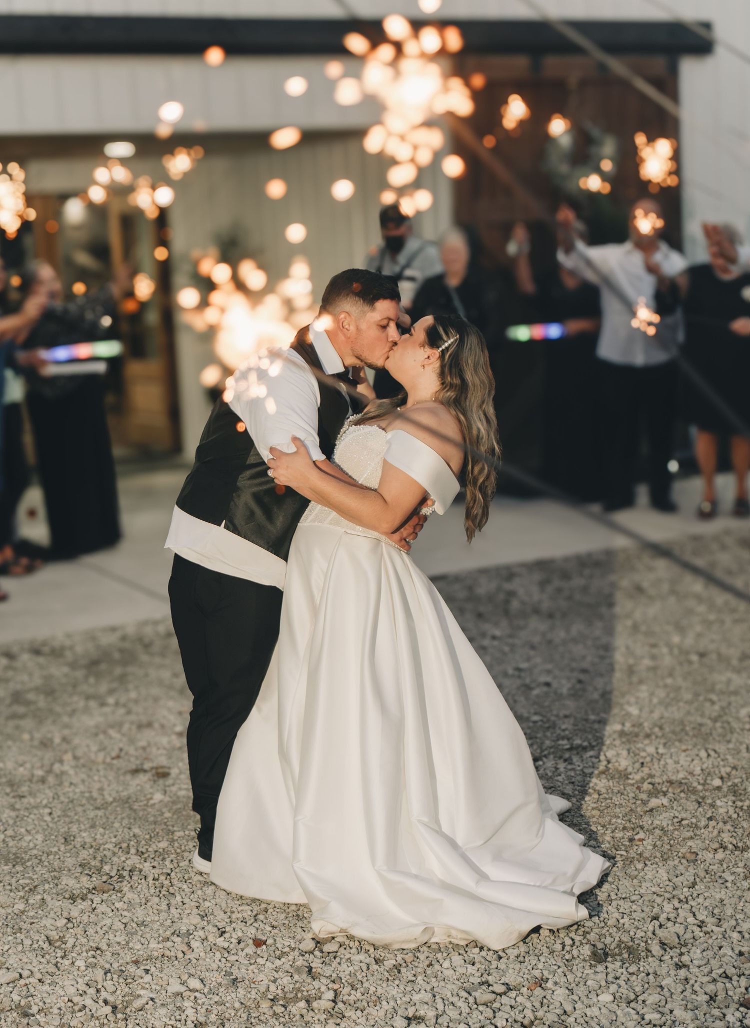 Bride and groom share a romantic kiss surrounded by sparklers during their outdoor wedding reception sendoff.