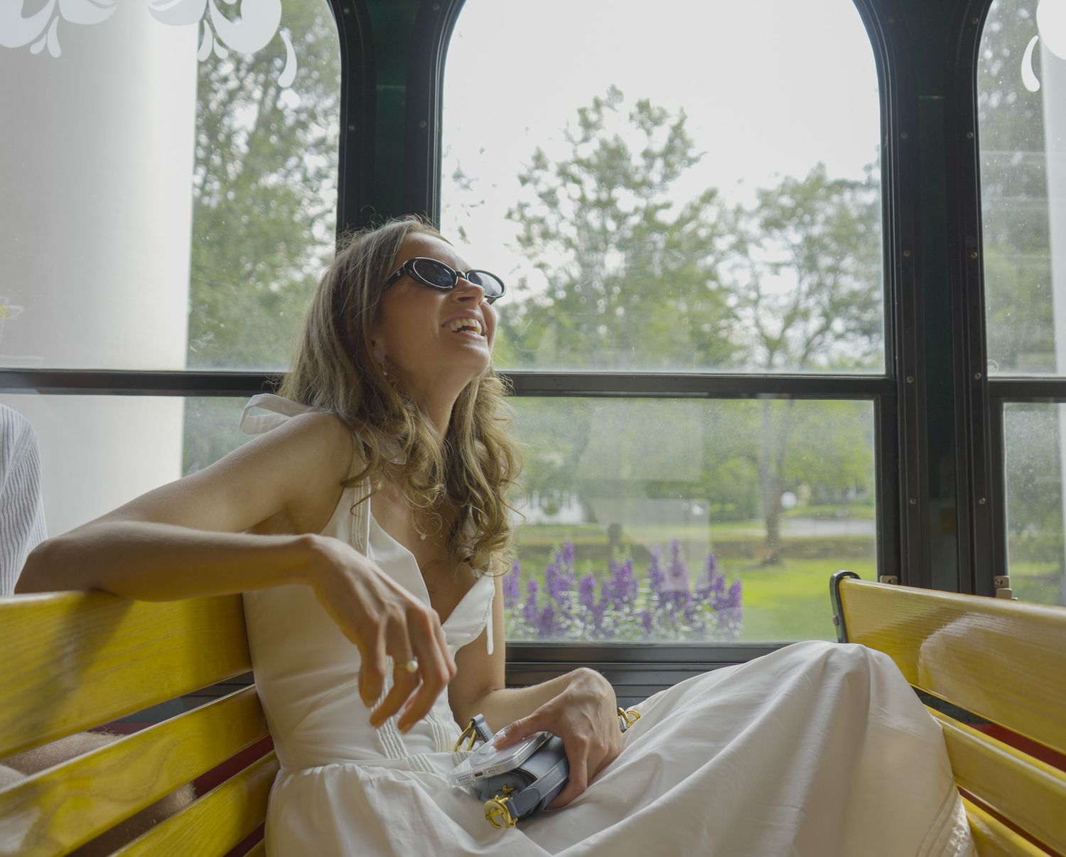 Candid and joyful lifestyle photography of a woman laughing on a yellow bench, captured with natural light by Shane Anthony.