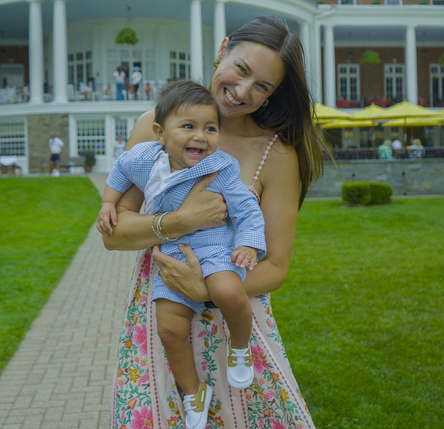 Authentic family photography of a smiling mother holding her laughing toddler outdoors, captured by Shane Anthony.