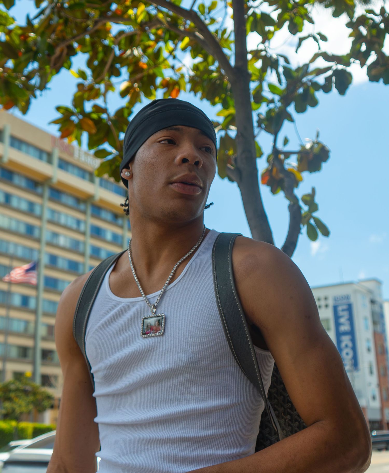 Low-angle urban lifestyle portrait of a man in streetwear against a city skyline, showcasing cinematic perspective by Shane Anthony.