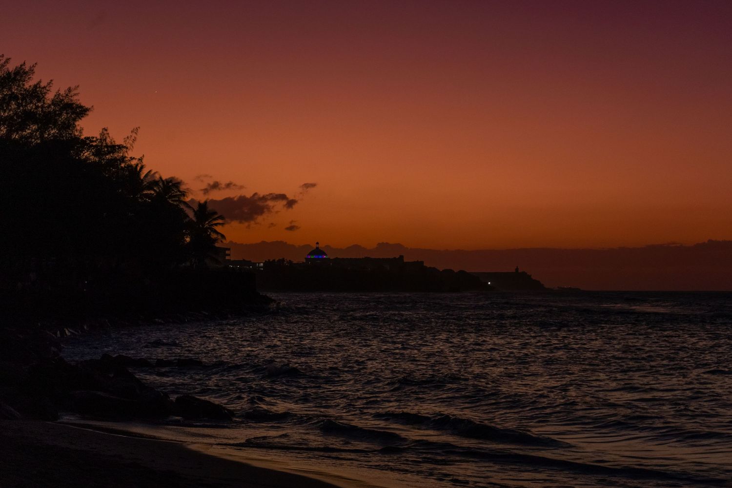 Cinematic landscape photography of a dark coastline during a deep orange sunset, illustrating moody storytelling by Shane Anthony.
