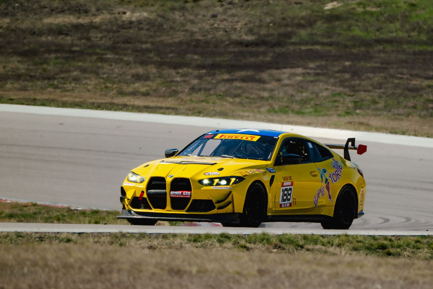 Yellow BMW M4 GT race car number 29 navigating a turn on a racing circuit.