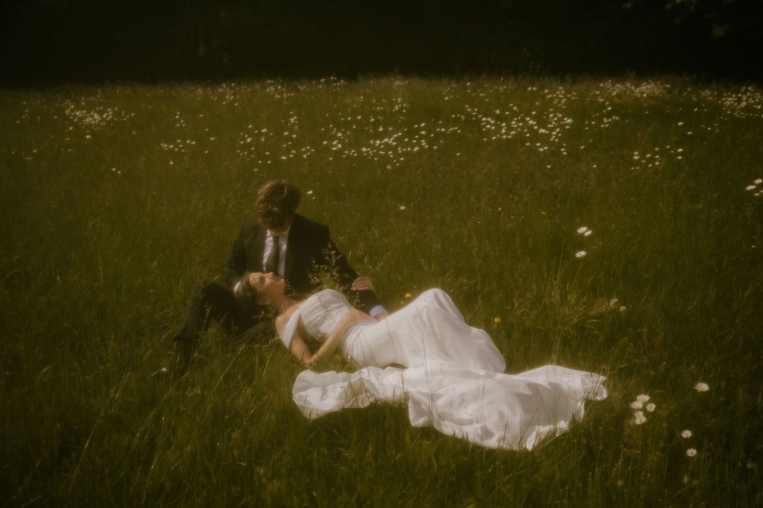 Romantic couple in wedding attire lying in a wildflower meadow on their wedding day.