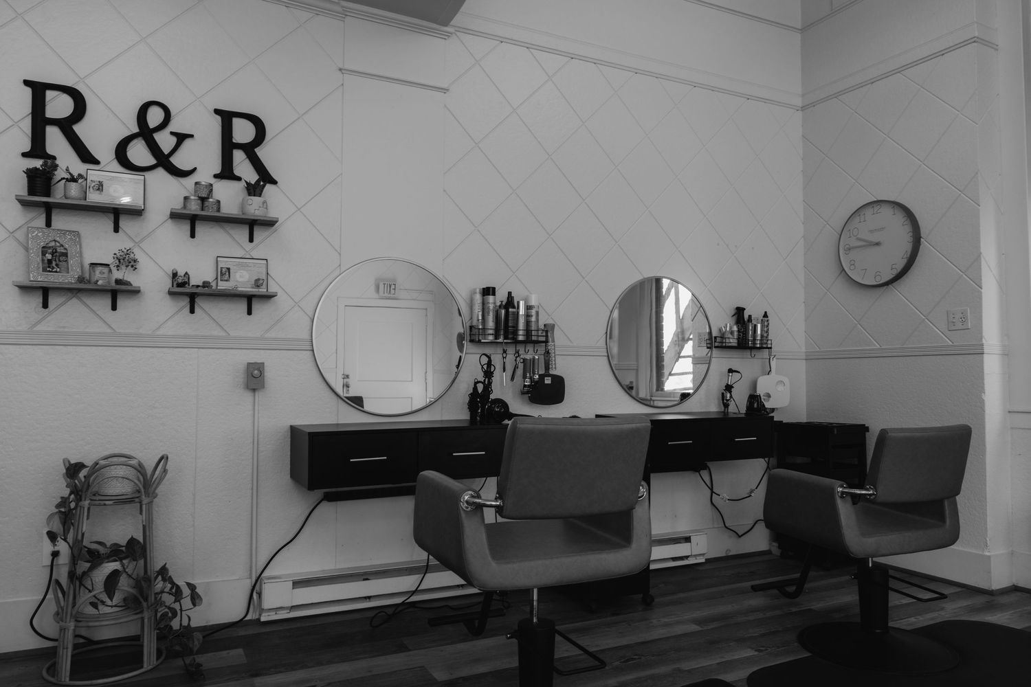 Black and white photo of R&R hair salon interior with round mirrors and styling chairs.