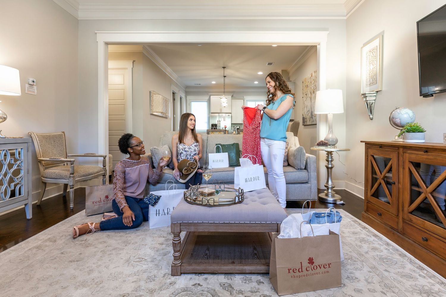 Three women holding up shopping bags on a sofa in a Savannah vacation rental living room
