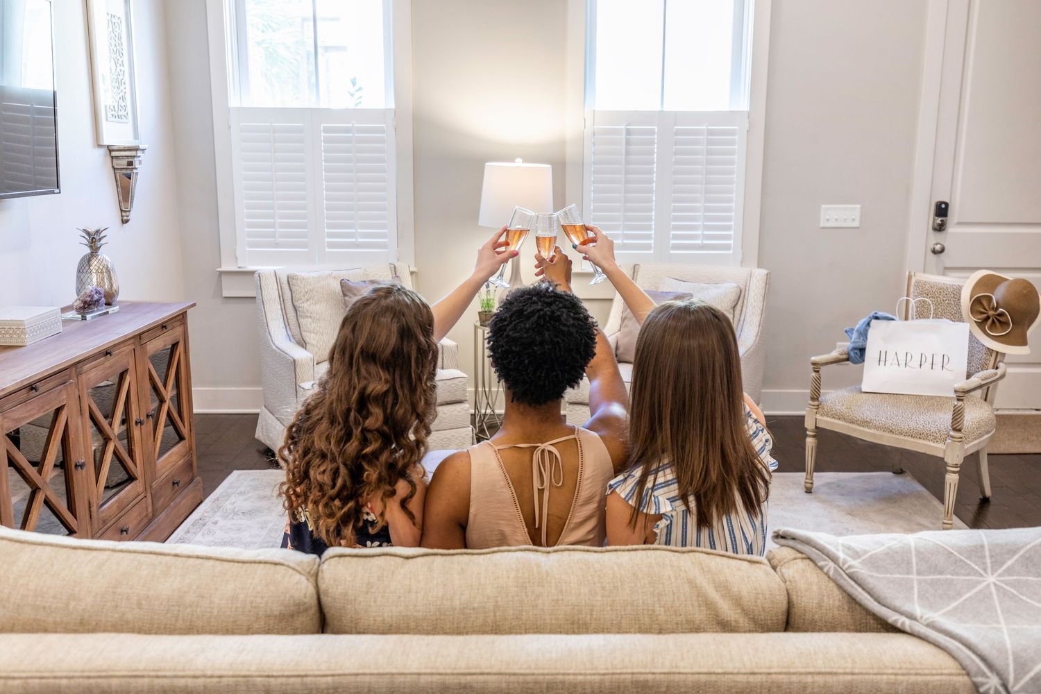 Three women toasting with wine glasses in the living room of a Savannah vacation rental