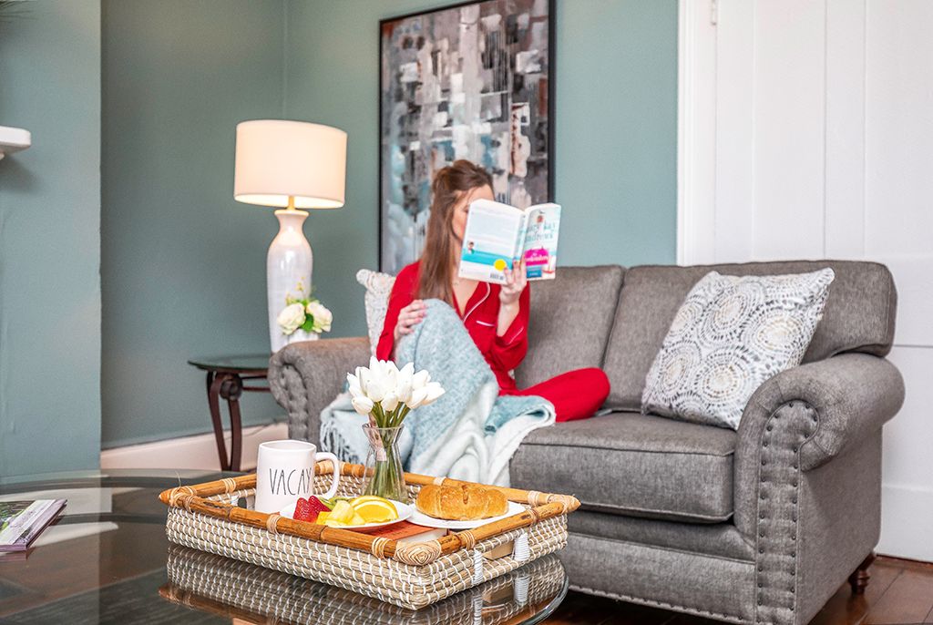 Woman reading on the sofa with a breakfast tray in the living room of a Savannah vacation rental