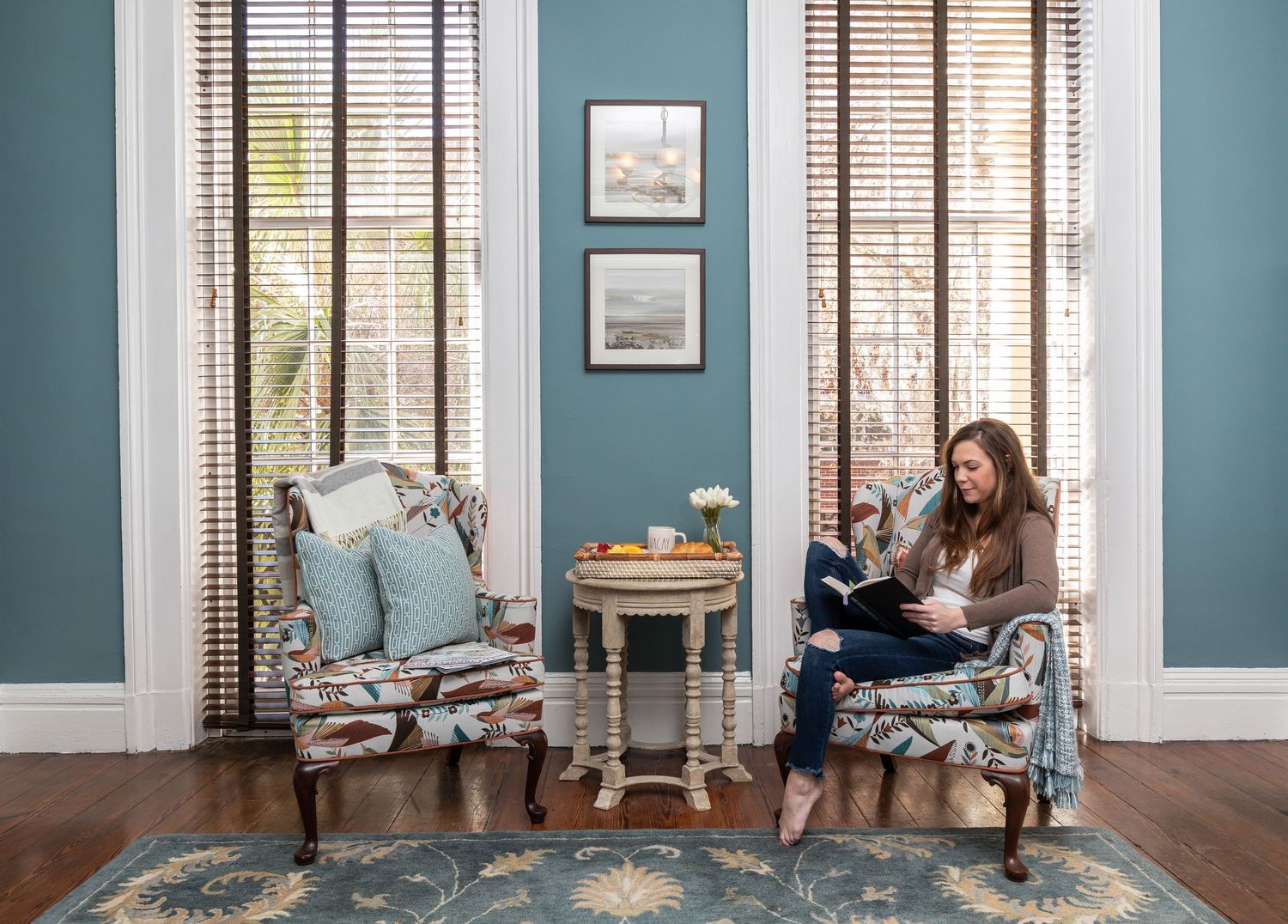 Woman reading on a chair with a breakfast tray in the living room of a Savannah vacation rental