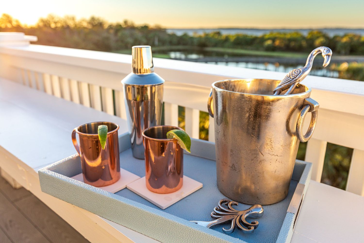 Cocktail tray with copper Moscow Mule mugs and a cocktail shaker on a deck overlooking the marsh at a Tybee Island vacation rental