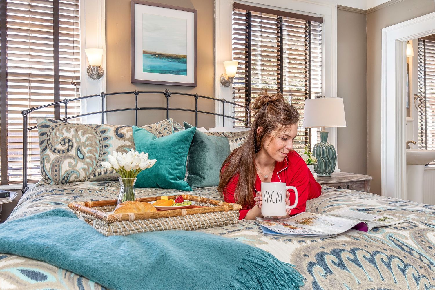Woman reading on a bed with a breakfast tray in a bedroom of a Savannah vacation rental