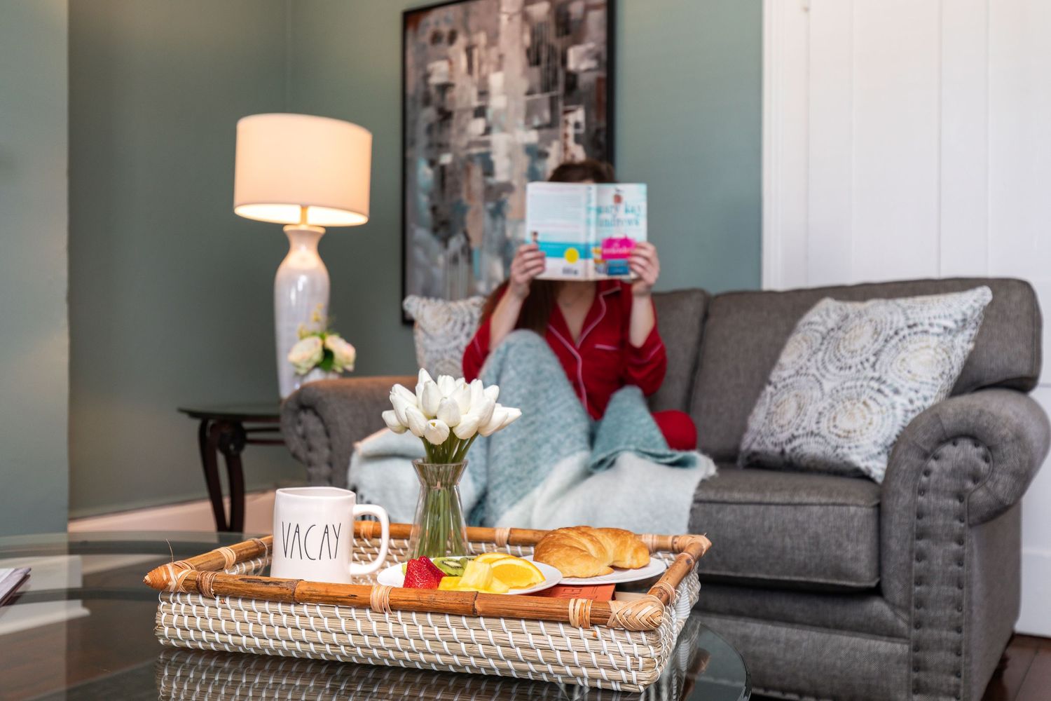 Woman reading on the sofa with a breakfast tray in the living room of a Savannah vacation rental