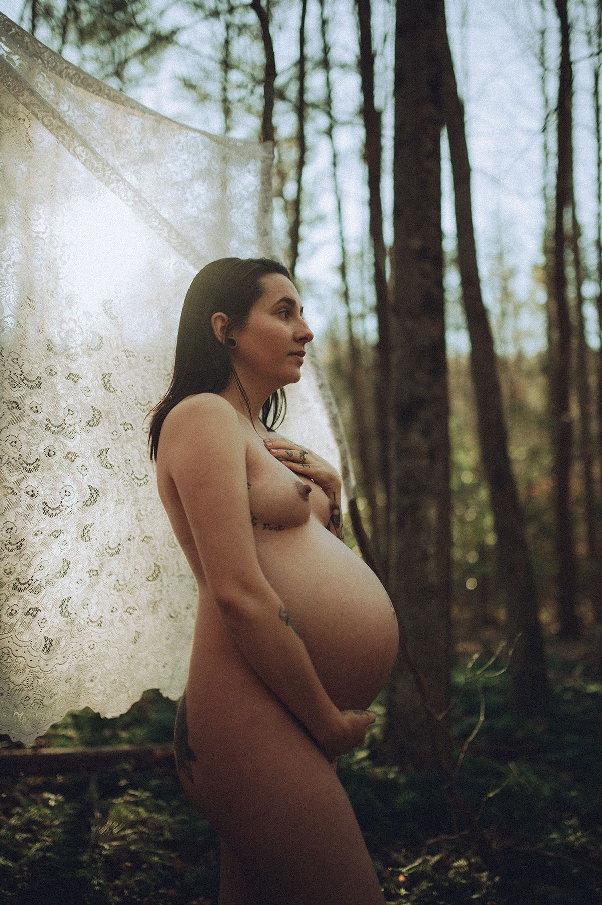 Artistic maternity boudoir photo series showing silhouette of pregnant woman in forest setting with ethereal lighting and shadows in NC.