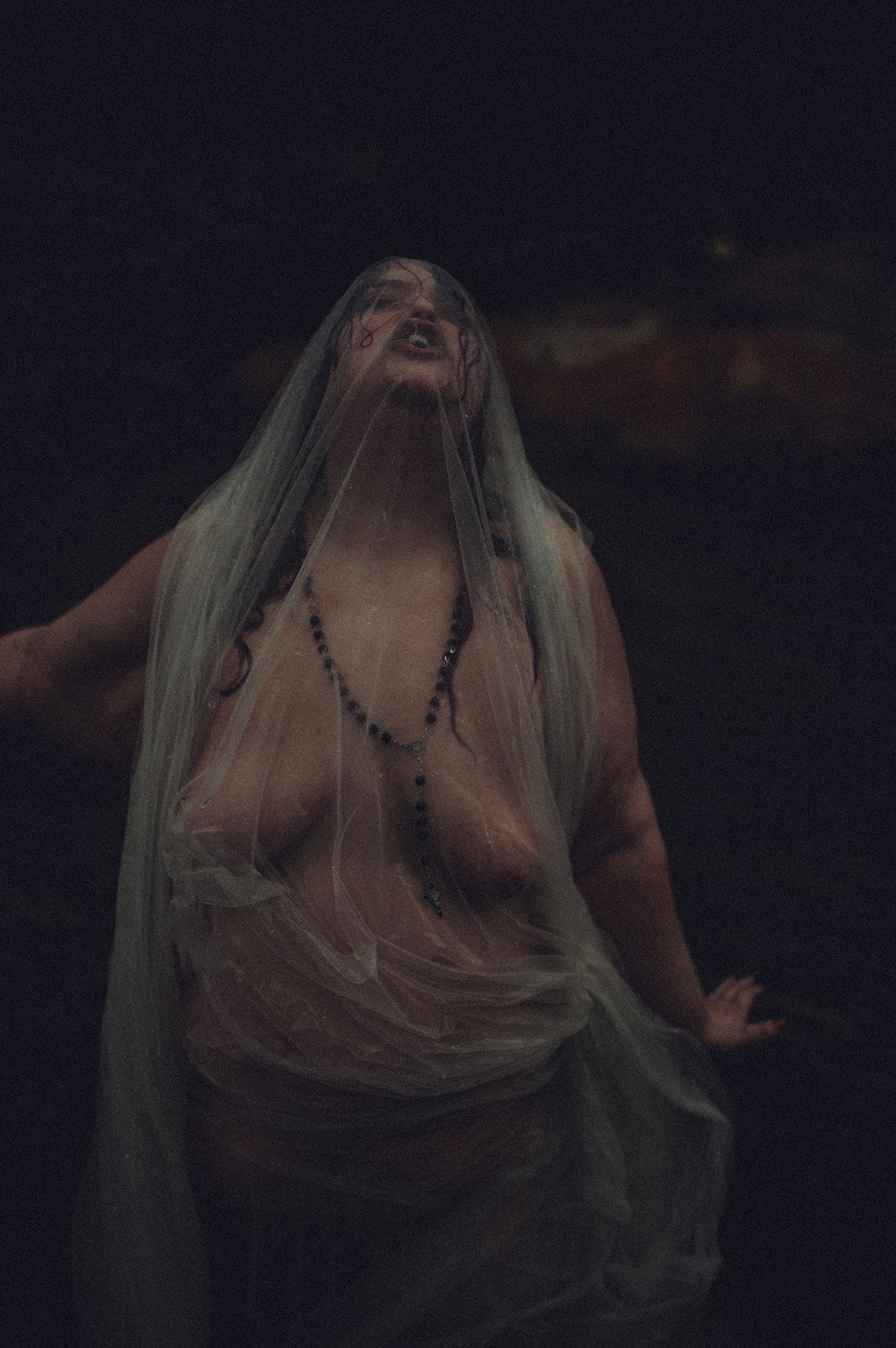 Dark and moody boudoir photo showing a figure draped in ethereal fabric against a black background near Spartanburg, South Carolina.