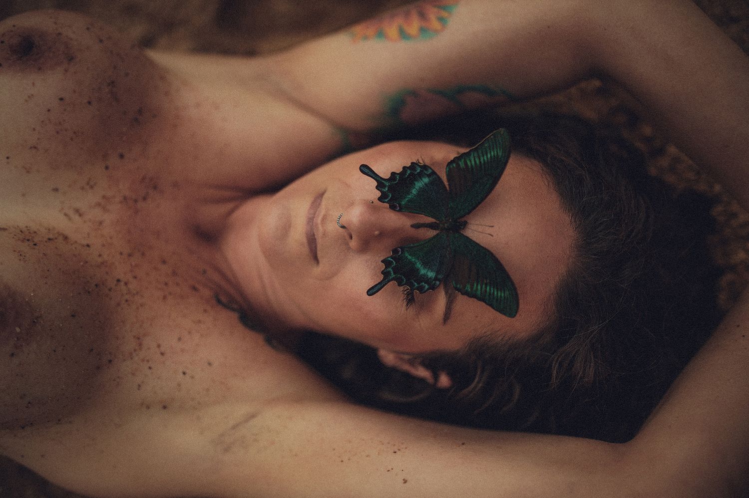 Artistic boudoir photograph showing a butterfly on skin in dark moody lighting in Spartanburg, South Carolina.
