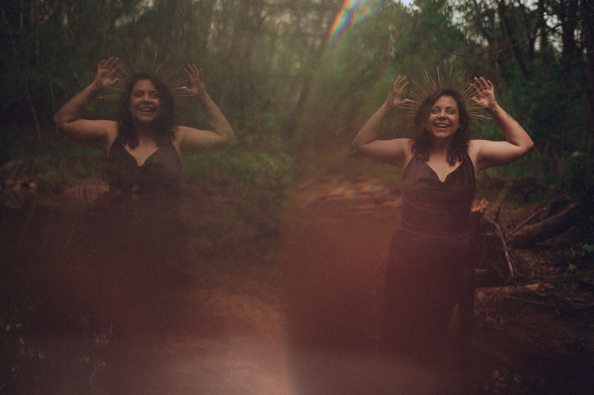 A playful boudoir portrait session in a sunlit forest with lens flares and warm golden tones creates a dreamy atmosphere in Spartanburg, SC.