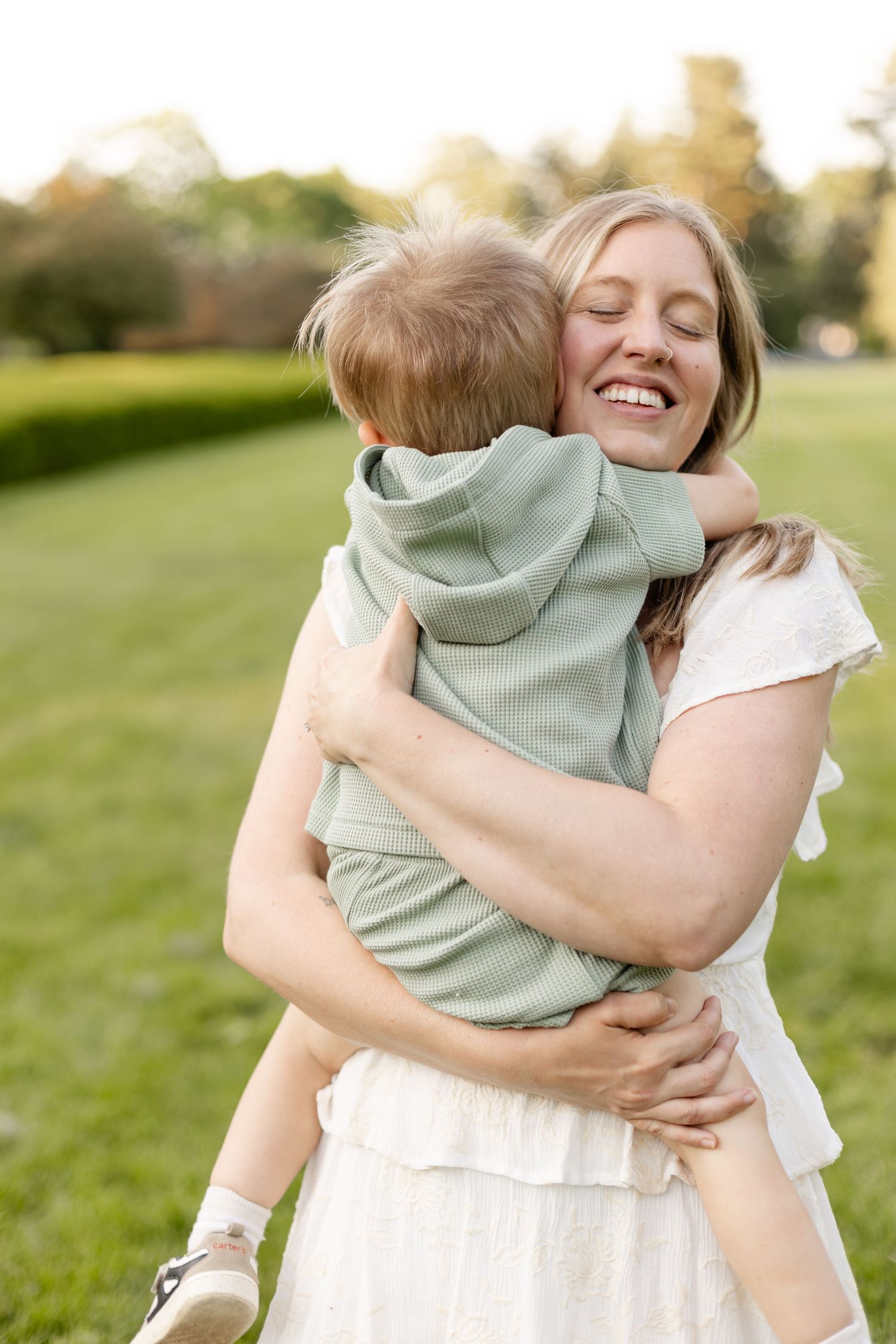 Candid moments of family embraces and laughter in a sunlit field during family photography session in Indianapolis by Katy Rose Photography.