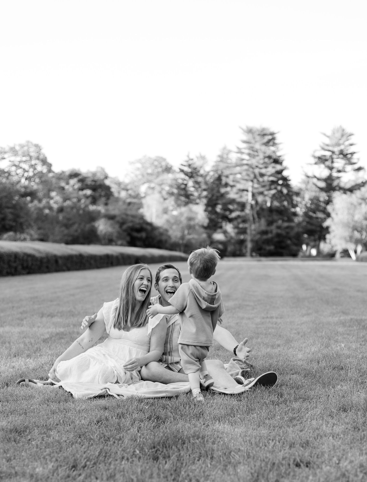 Black and white photo of a family sharing joyful moments on a grassy hillside during family photos in Indianapolis by Katy Rose Photography.